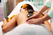 Stone therapy. Woman getting a hot stone massage in spa salon