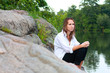 A lonely young woman sitting on rocks on the river