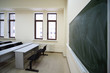 Big green school board inside empty beige classroom