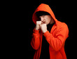furious young man in orange sweatshirt, black background