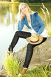 young woman sitting on stone at pond