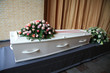 White coffin with pink sympathy flowers