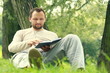 Young man reading book in the park, dolly shot