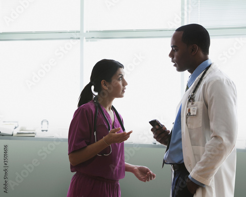 Photo: Doctor and nurse talking in hospital hallway Doctor and nurse talking in hospital hallway