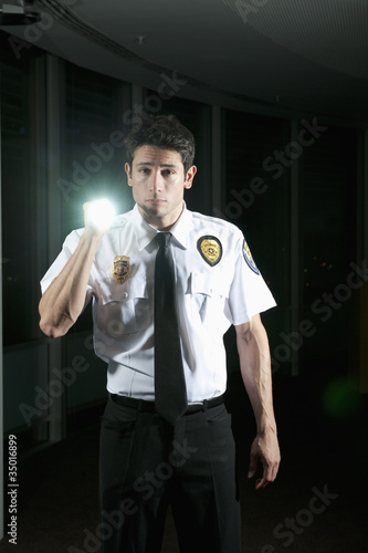 Photo: Hispanic security guard checking dark offices Hispanic security guard checking dark offices