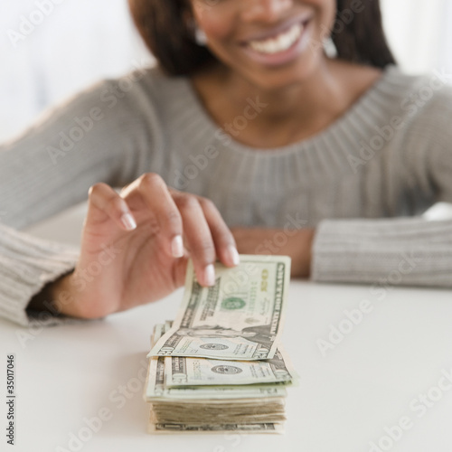 Photo: Mixed race woman taking money from stack Mixed race woman taking money from stack
