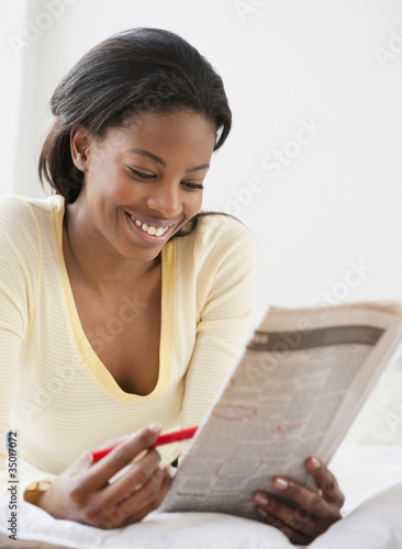 Photo: Mixed race woman reading classified ads Mixed race woman reading classified ads