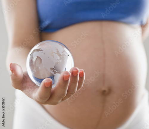 Photo: Pregnant Hispanic woman holding glass globe Pregnant Hispanic woman holding glass globe