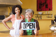 African American business owners in cafe holding open sign