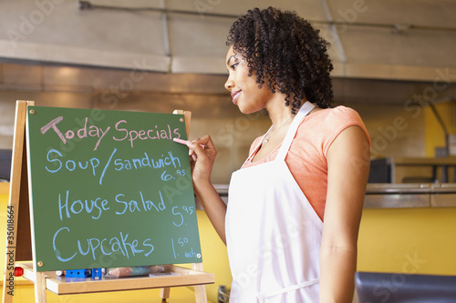 Photo: African American business owner writing cafe specials on blackboard African American business owner writing cafe specials on blackboard