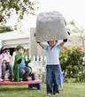 Korean boy as superheros lifting large boulder