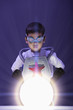 Korean boy in superhero costume looking at glowing orb
