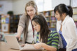 Librarian helping students with research in school library