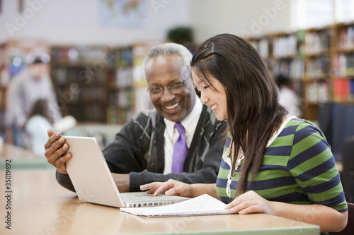 Photo: Librarian helping student do research in school library Librarian helping student do research in school library