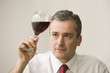 Caucasian businessman looking at glass of red wine
