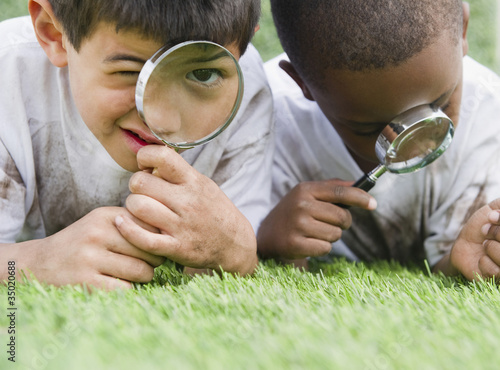 Photo: Boys looking at grass through magnifying glasses Boys looking at grass through magnifying glasses
