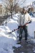 Mixed race man shoveling snow from sidewalk