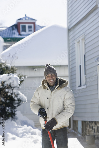 Photo: Mixed race man shoveling snow off driveway Mixed race man shoveling snow off driveway