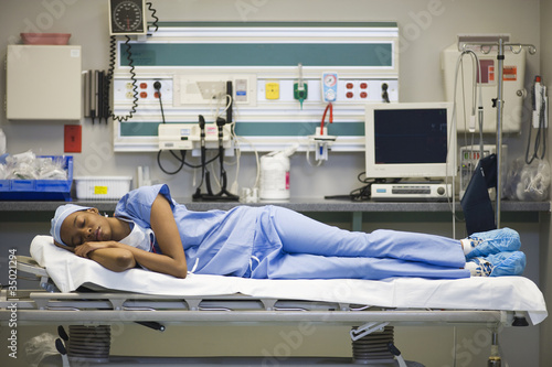Photo: Tired black surgeon laying on hospital gurney Tired black surgeon laying on hospital gurney