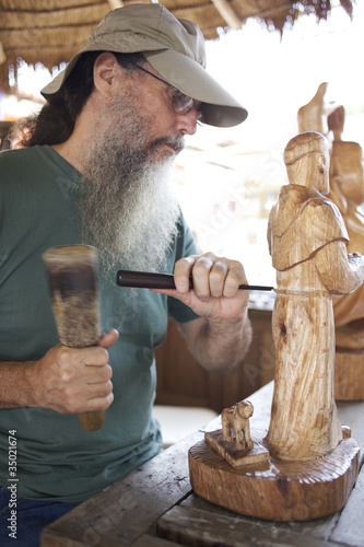 Photo: Mixed race man carving wooden statue Mixed race man carving wooden statue