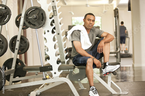 Photo: African American man resting in health club on weight-lifting bench African American man resting in health club on weight-lifting bench