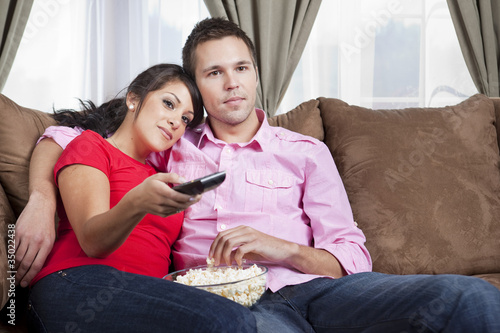 Photo: Couple sitting on sofa and watching television Couple sitting on sofa and watching television