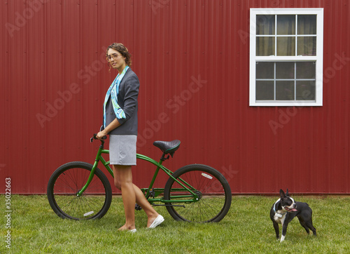 Photo: Mixed race businesswoman standing with bicycle and dog Mixed race businesswoman standing with bicycle and dog