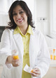 Smiling Hispanic pharmacist holding out prescription bottle