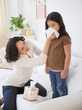 Mother wiping sick daughter’s nose with tissue