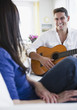 Mixed race man playing guitar for wife