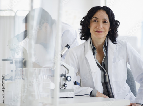 Photo: Hispanic researcher in laboratory next to microscope Hispanic researcher in laboratory next to microscope