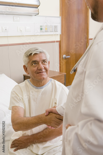 Photo: Doctor shaking patient’s hand in hospital room Doctor shaking patient’s hand in hospital room