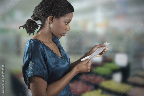 Photo: Black woman looking at grocery shopping list Black woman looking at grocery shopping list