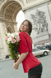 Caucasian woman holding bouquet near Arc de Triomphe