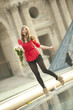 Caucasian woman standing near fountain with bouquet at the Louvre