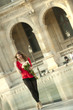 Caucasian woman standing near fountain with bouquet at the Louvre