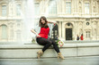 Caucasian woman sitting on fountain with bouquet at the Louvre