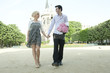 Caucasian couple holding hands in park near Notre Dame