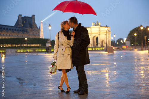 Photo: Caucasian couple kissing in rain at night near the Louvre Caucasian couple kissing in rain at night near the Louvre