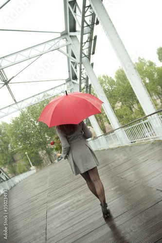 Photo: Caucasian woman walking in rain with red umbrella Caucasian woman walking in rain with red umbrella