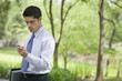 Hispanic businessman using cell phone in park