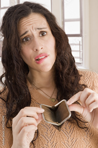 Photo: Mixed race woman opening empty coin purse Mixed race woman opening empty coin purse