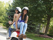 Hispanic friends riding scooter together