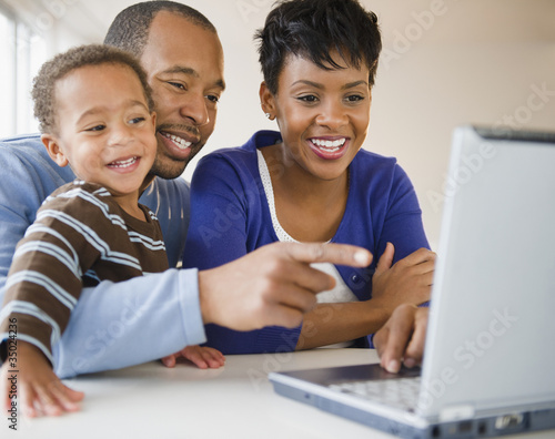 Photo: Black family using laptop together Black family using laptop together
