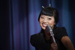 Elegant Asian woman singing into microphone