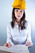 Engineer woman in yellow helmet with plans