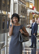 Photo: Black businesswoman talking on cell phone next to arrival departure board in airport Black businesswoman talking on cell phone next to arrival departure board in airport