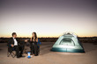 Couple in formal attire toasting champagne glasses outside tent in desert