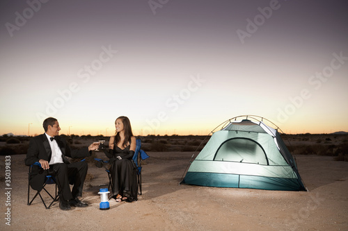 Photo: Couple in formal attire toasting champagne glasses outside tent in desert Couple in formal attire toasting champagne glasses outside tent in desert