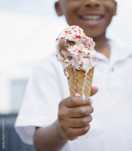 Photo: Close up of smiling Black boy holding melting ice cream cone Close up of smiling Black boy holding melting ice cream cone